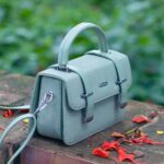 A stylish handbag sits outdoors on a stone wall.